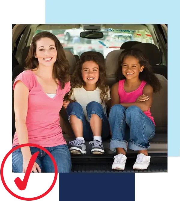 We're driving possibility. Image of mother in pink blouse and jeans and two daughters smiling at camera while sitting in the back of their van.